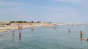 Ein Strand mit badenden und sonnenden Personen.