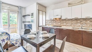 Eine moderne Küche mit weißen Schränken, einer gefliesten Spritzschutzwand und einem Essbereich mit Tisch für vier Personen.