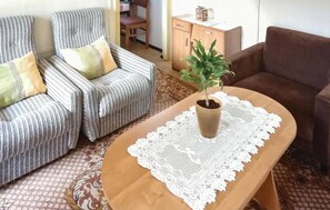 Relax in a comfortable seating area with a striped armchair and sofa, surrounded by a potted plant and storage space.