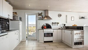 A modern kitchen with white cabinetry, a stove, and a microwave. There is a door leading to a balcony with a view of the outside.