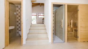 A staircase leading to a room with a sauna, a tiled wall, and a wooden door.