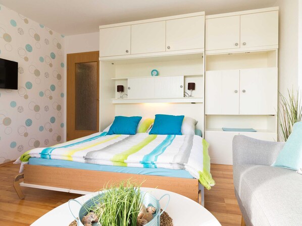 A bedroom with a bed, a bedside table, a chair, and a wardrobe.