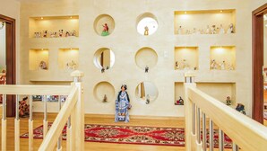 En lobby med en central trappe, flere udstillingsmontre med figurer og et stort spejl.