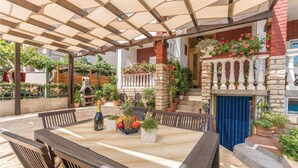 An outdoor patio with a wooden pergola, a stone fireplace, and various potted plants. - Gorgeous apartment in Biograd with WiFi (Biograd)