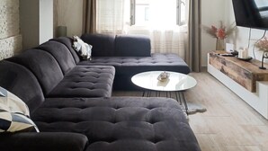 A modern living room with a sectional sofa, a small round coffee table, and a flat-screen TV on a wooden console. - Gorgeous apartment in Biograd with WiFi (Biograd)