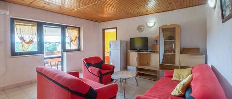A cozy living room with red sofas, a television, and a wooden ceiling.