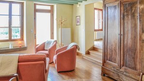 A room with a wooden cabinet, a chair, a lamp, and a window. - Nice home in Landreville with kitchen (Landreville)