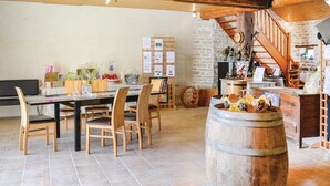 A rustic dining area with wooden chairs and a large barrel centerpiece, a stone wall, and a wooden staircase. - Nice home in Landreville with kitchen (Landreville)