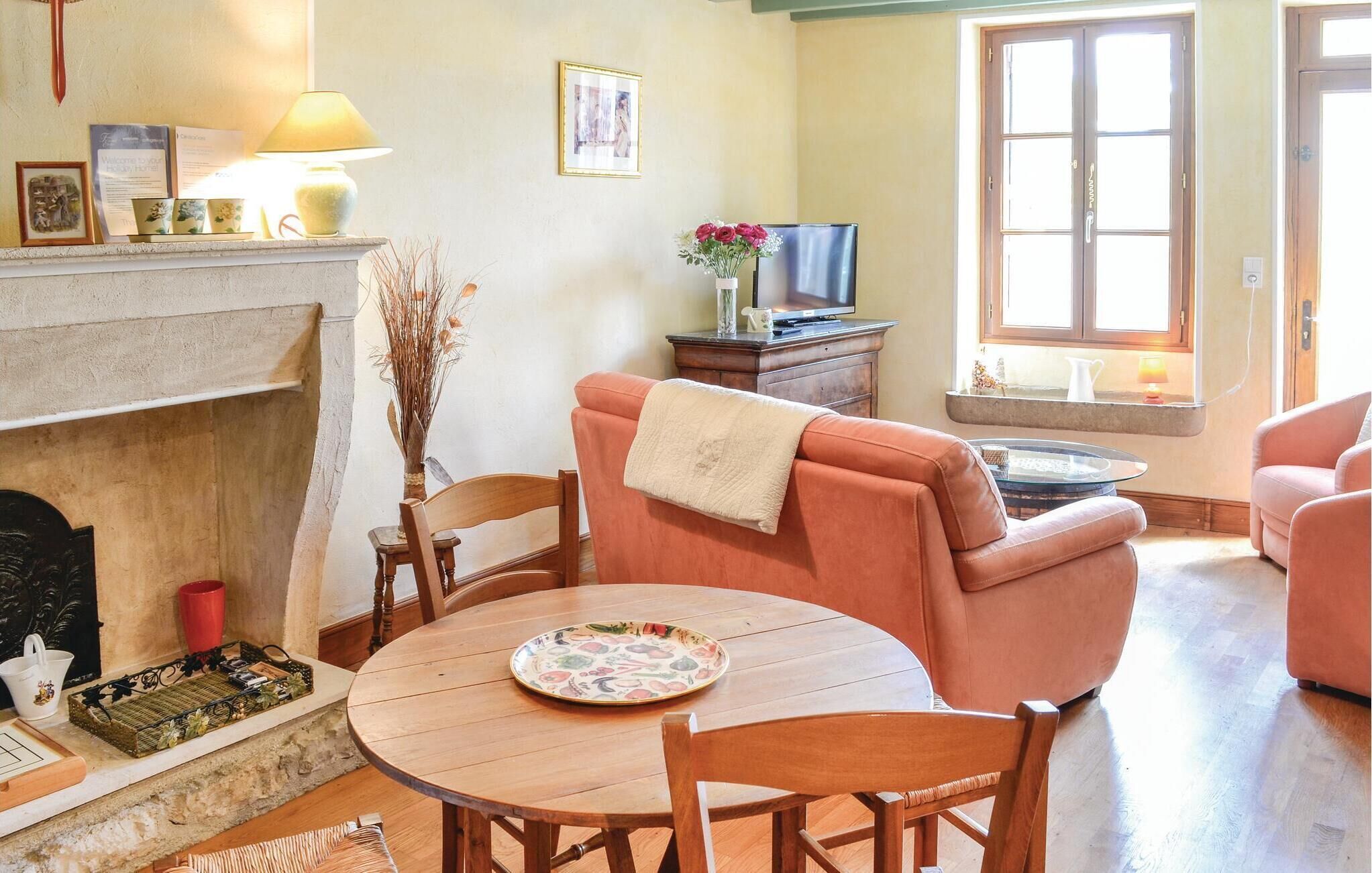 A cozy living room with a fireplace, a round wooden table, and comfortable seating.