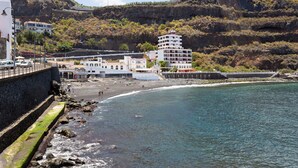 A coastal town with buildings along the beach, rocky cliffs, and a clear view of the sea.