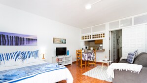 A hotel room with a bed, a sofa, a dining area, and a kitchen.