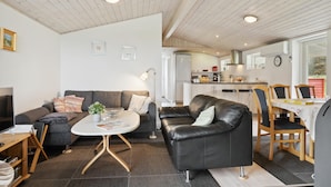 Uma sala de estar moderna com sofá, mesa de centro e área de jantar com cadeiras e mesa.