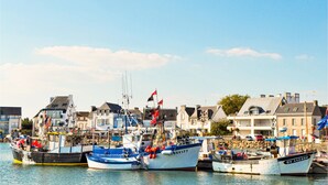 Ein Hafen mit mehreren vertäuten Booten, umgeben von Gebäuden mit Balkonen und einem klaren Himmel.