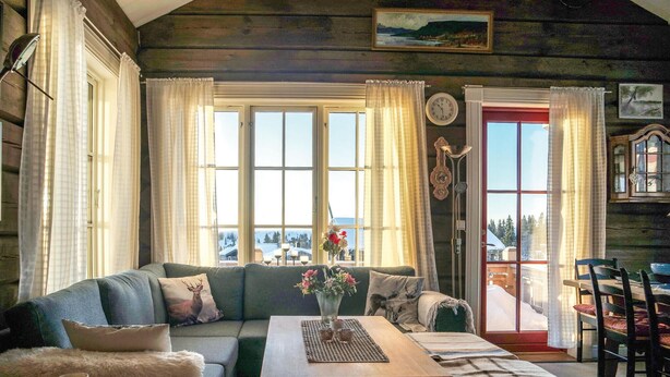 Een gezellig interieur van een vakantiehuisje, met een bank, een houten tafel en een eethoek.