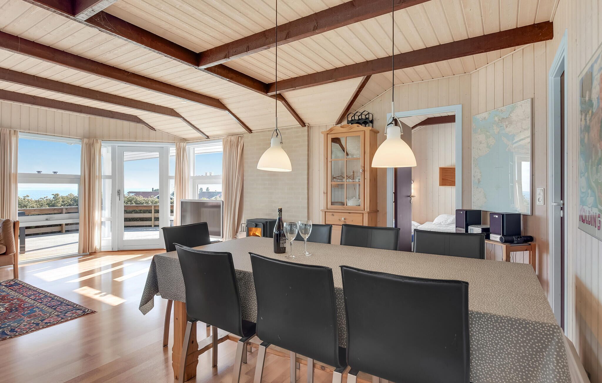 A spacious dining area with a long table, black chairs, and pendant lighting.