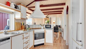 A modern kitchen with white cabinets, a granite countertop, a built-in oven, and a microwave. There is a window providing natural light and a view of the outside. - Stunning home in Sjølund with kitchen (Sjølund)