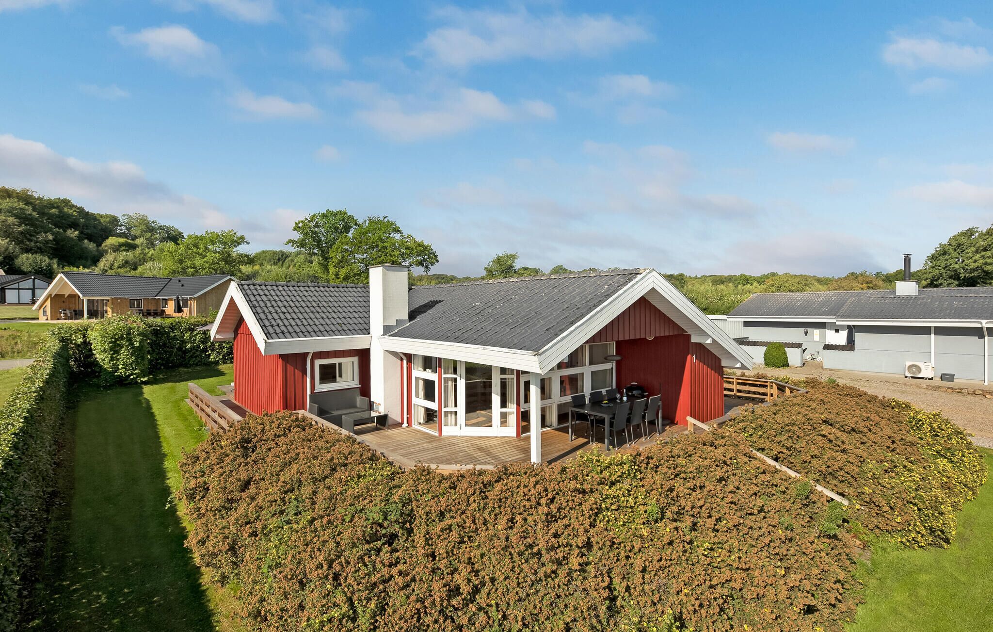 A red and white building with a covered patio area and a large garden in front.