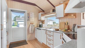 A compact kitchen with wooden cabinets, a sink, and a window overlooking a garden. - Stunning home in Sjølund with kitchen (Sjølund)