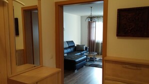 Ein modernes Wohnzimmer mit einer schwarzen Ledersofa, einem Glastisch und einer Chandelüster.
