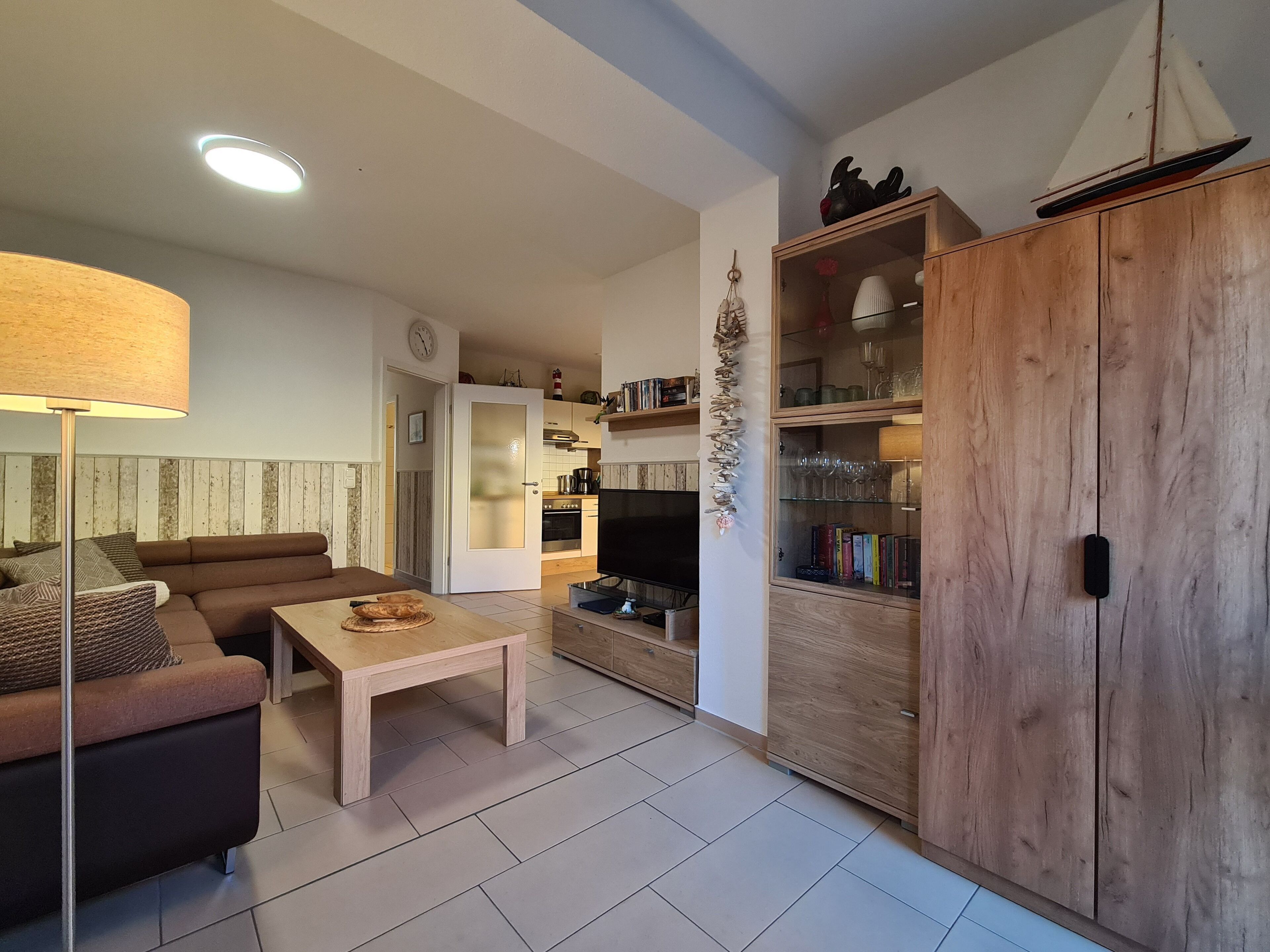A modern living room with a sofa, a coffee table, a TV, and a wooden cabinet with glass doors.