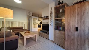 A modern living room with a sofa, a coffee table, a TV, and a wooden cabinet with glass doors.