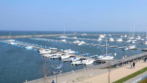 Un porto turistico con numerose imbarcazioni ormeggiate, una passeggiata lungo l'acqua e una vista aperta sul mare.