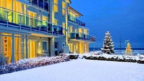 Un hotel a più piani con balconi, un paesaggio innevato e un albero di Natale.