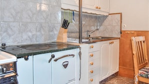 A kitchen with a stove, sink, and cabinets.