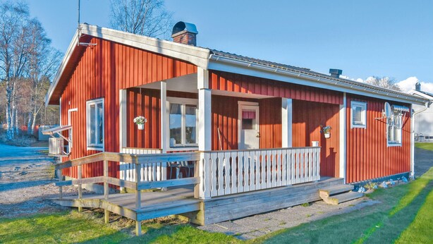 A red wooden house with a porch and a small deck.
