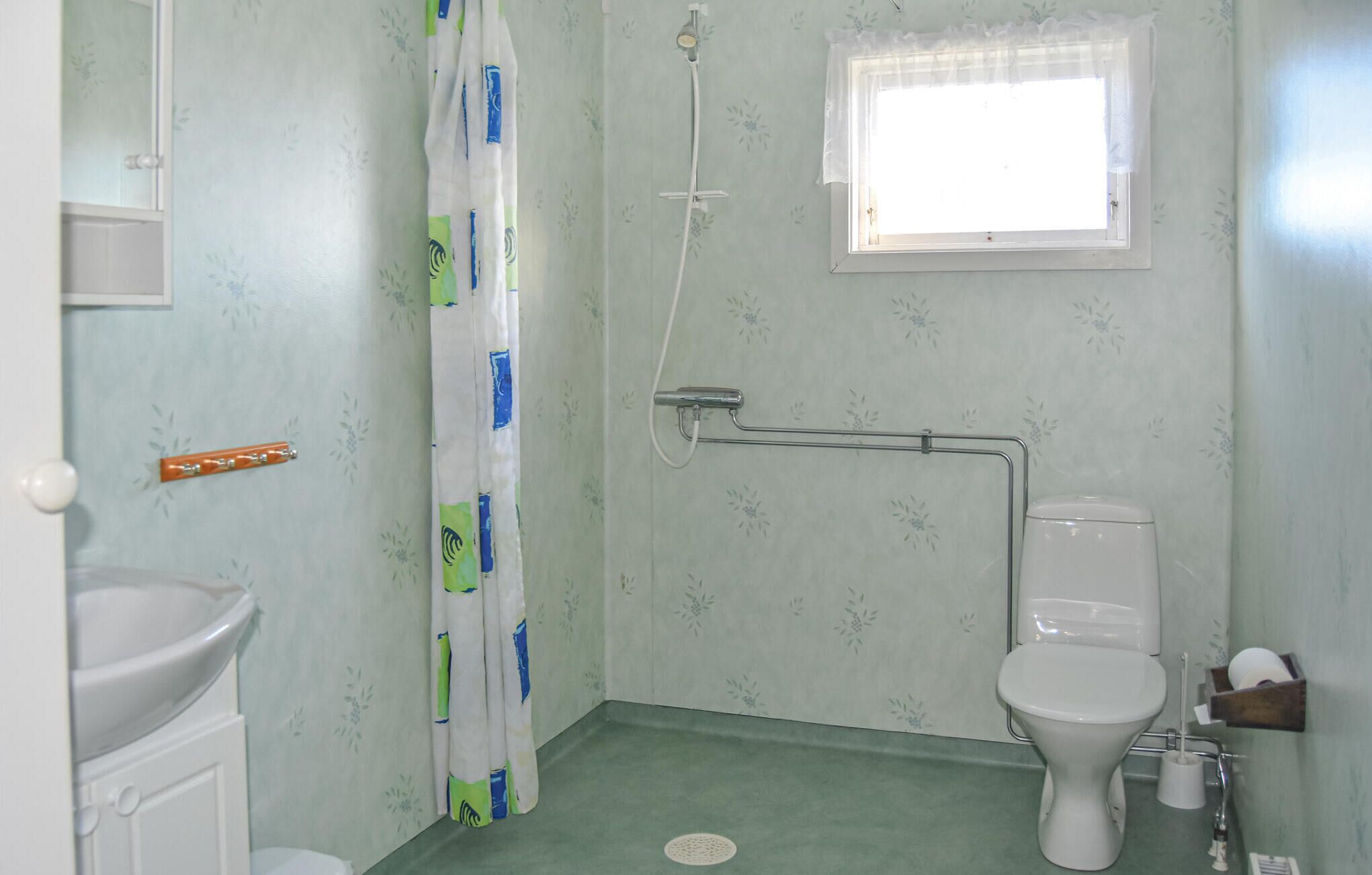 Une salle de bain comprenant des toilettes, une douche, un lavabo et une fenêtre.