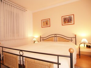 Ein Schlafzimmer mit einem Bett, zwei Nachttischlampen und zwei gerahmten Bildern an der Wand.
