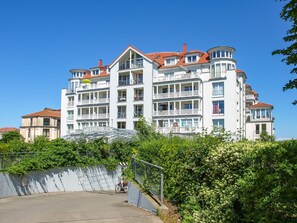 Ein mehrstöckiges Hotel mit Balkonen, einem überdachten Gang und üppiger Bepflanzung.