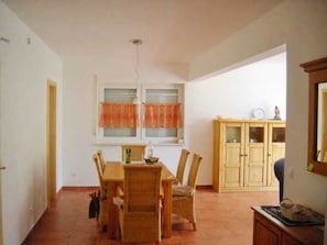 Un coin repas comprenant une table et des chaises en bois, une fenêtre avec des rideaux et un meuble avec des portes en verre.