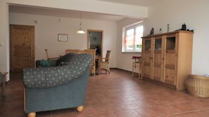 Un salon comprenant un canapé, un meuble en bois et un coin repas avec une table et des chaises.