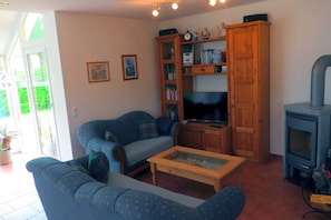 Un salon comprenant un canapé, une table basse, un téléviseur, un meuble en bois et une cheminée.