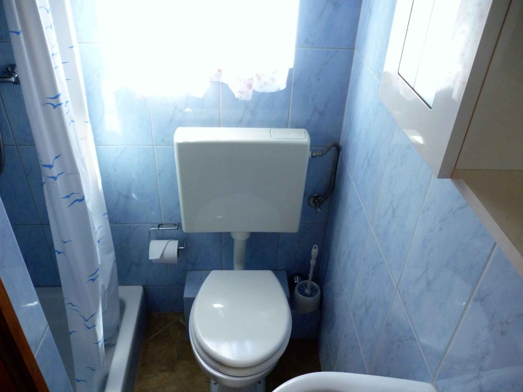 A small bathroom with a toilet, a toilet paper holder, and a bidet.