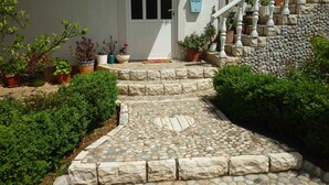 A stone staircase leading to a white door, surrounded by potted plants and a stone wall. - Studio mit Klimaanlage und Balkon (Seline)