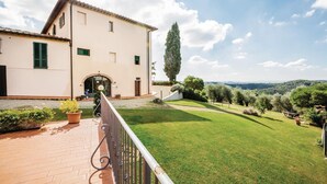 A large, single-story building with a tiled roof and a paved patio area. - Cozy apartment in Castelfiorentino FI (Castelfiorentino FI)