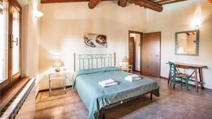 A bedroom with a bed, a chair, a table, a painting, and a mirror. - Cozy apartment in Castelfiorentino FI (Castelfiorentino FI)
