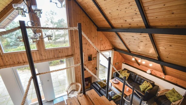 Un interior de madera con un altillo, un sofá de cuero negro y una mesa de comedor.