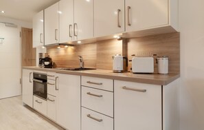 A modern kitchen with white cabinets, stainless steel appliances, and a wooden countertop. - Cozy apartment in Binz with house sea view (Prora/Rügen)