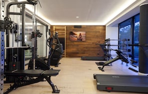 Uma academia com equipamentos de cardio, máquinas de musculação e esteira.