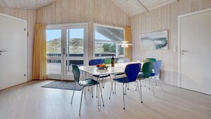 A dining area with a table and chairs, large windows, and a view of the outdoors.