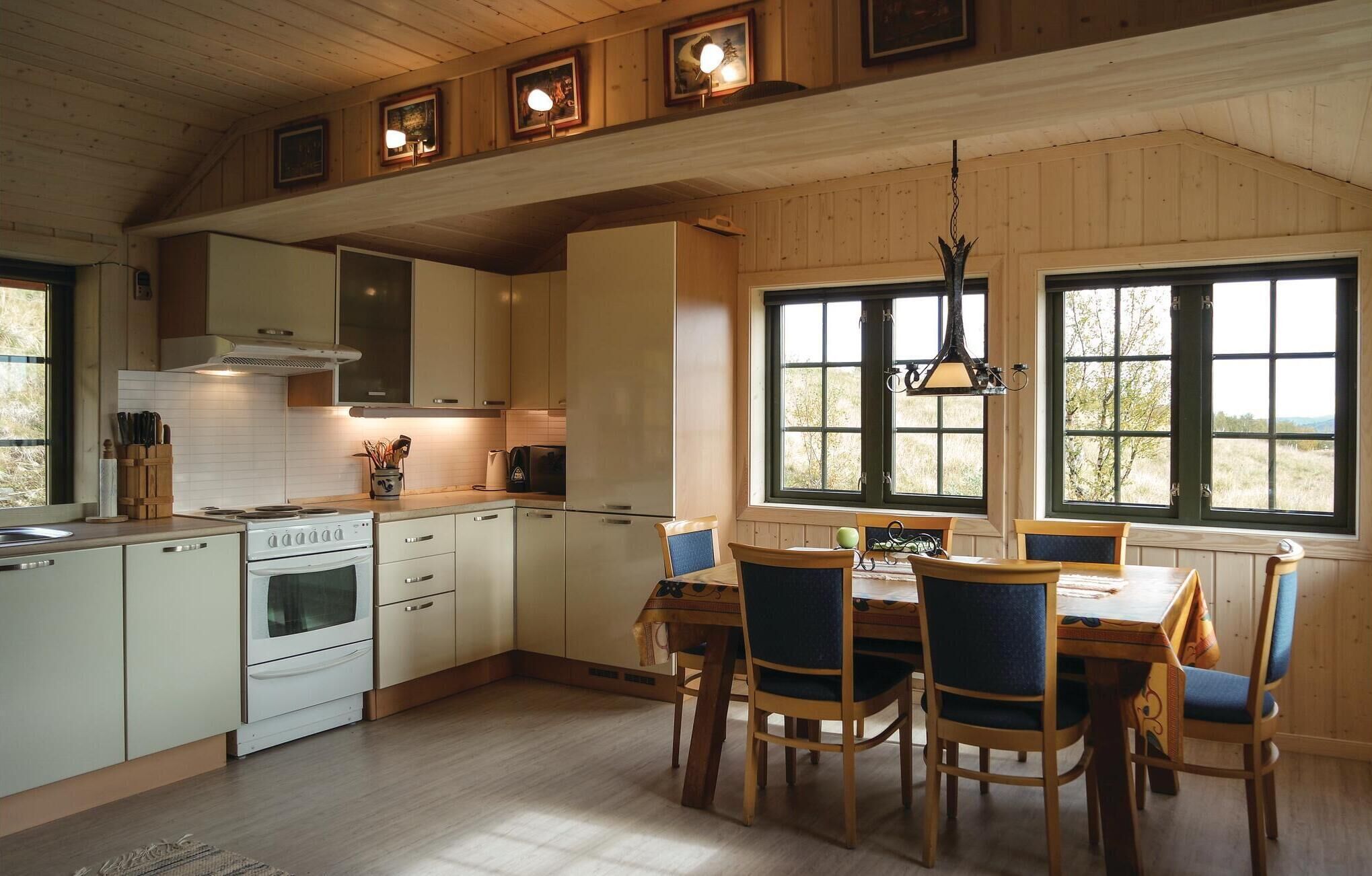 Une cuisine avec des meubles de rangement en bois, une cuisinière et un coin repas comprenant des chaises et une table.