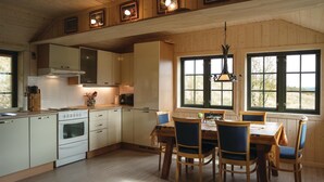 Una cocina con armarios de madera, una estufa y un comedor con sillas y una mesa.