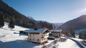 Ein schneebedecktes Bergresort mit Chalet-ähnlichen Gebäuden, einer Skipiste und freiem Blick auf die umliegenden Berge.