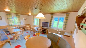 Ein gemütliches Zimmer mit Holzbalkendecke, einem runden Tisch und mehreren Stühlen.