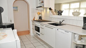 Uma cozinha moderna com armários brancos, bancada preta e lava-louças embutida.