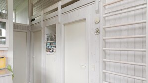 Um corredor com paredes de madeira branca, uma porta branca e um campainha branco.