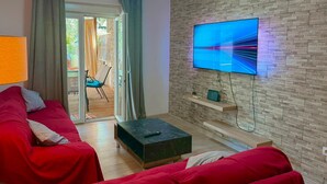 A living room with a red sofa, a TV mounted on a stone wall, and a sliding glass door leading to an outdoor area. - Gorgeous home in Pula with WiFi (Pula)